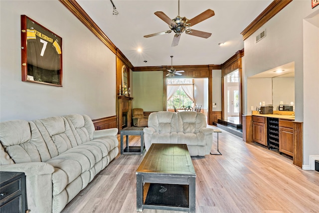 living room featuring ornamental molding, bar, beverage cooler, and light hardwood / wood-style floors