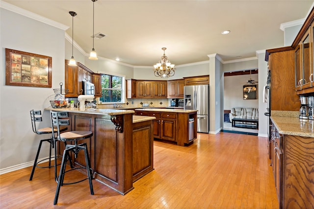 kitchen featuring ornamental molding, appliances with stainless steel finishes, a kitchen bar, kitchen peninsula, and light hardwood / wood-style flooring