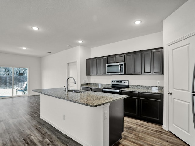 kitchen with stainless steel appliances, dark hardwood / wood-style flooring, sink, and a center island with sink