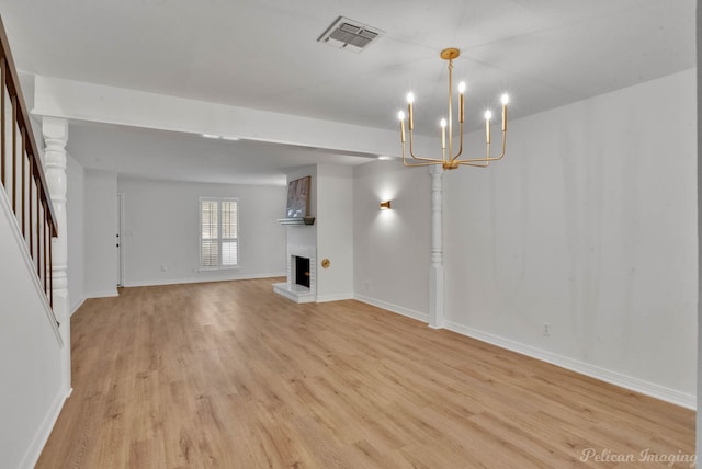 unfurnished living room with light wood-type flooring, a chandelier, and a fireplace