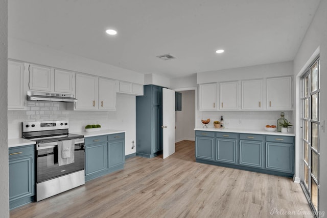 kitchen featuring light hardwood / wood-style flooring, blue cabinets, white cabinets, decorative backsplash, and electric range