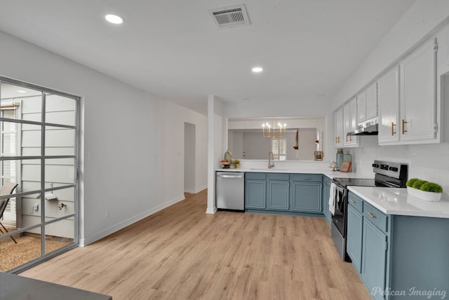 kitchen with stainless steel appliances, an inviting chandelier, plenty of natural light, sink, and light wood-type flooring