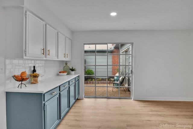 kitchen with blue cabinetry, plenty of natural light, light hardwood / wood-style floors, and backsplash