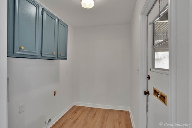 clothes washing area with hookup for an electric dryer, light hardwood / wood-style flooring, and cabinets