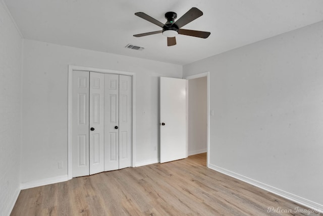 unfurnished bedroom with light wood-type flooring, ceiling fan, and a closet