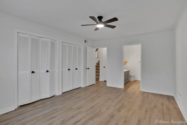 unfurnished bedroom featuring two closets, ensuite bathroom, ceiling fan, and light hardwood / wood-style floors