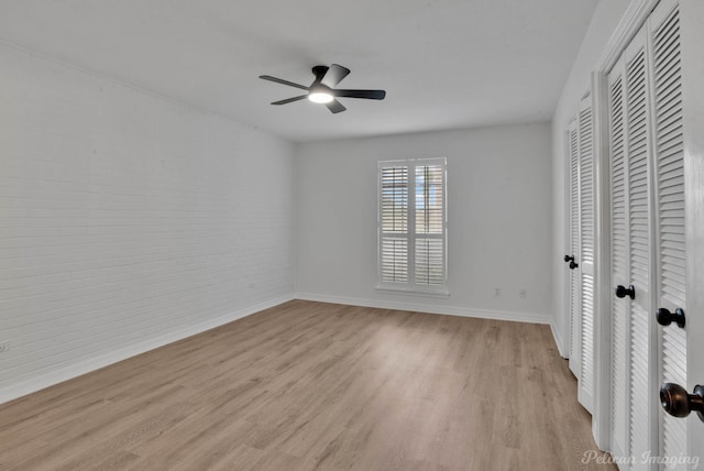 unfurnished bedroom featuring light hardwood / wood-style floors, ceiling fan, and brick wall