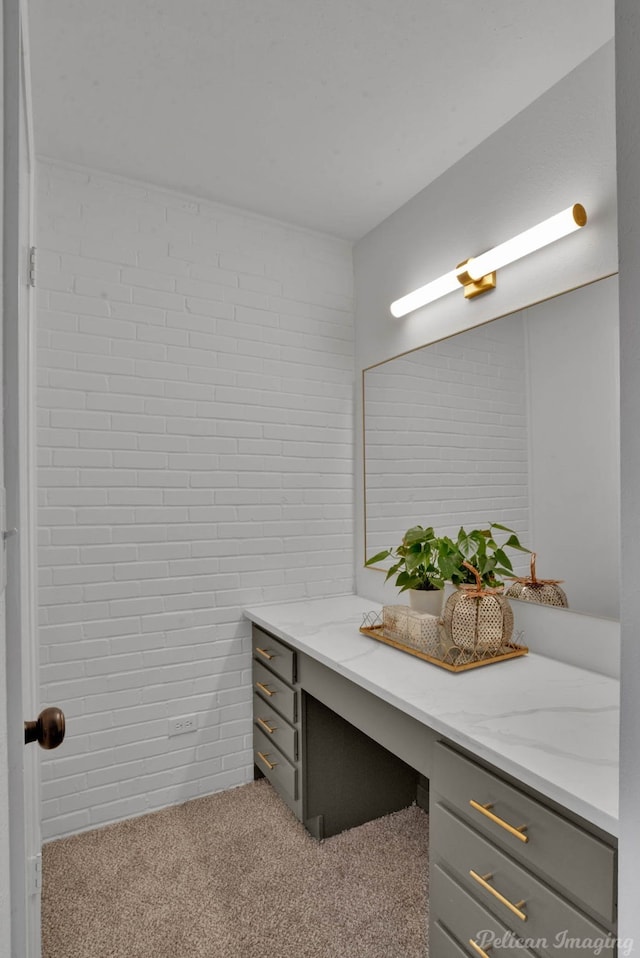 bathroom with vanity and brick wall