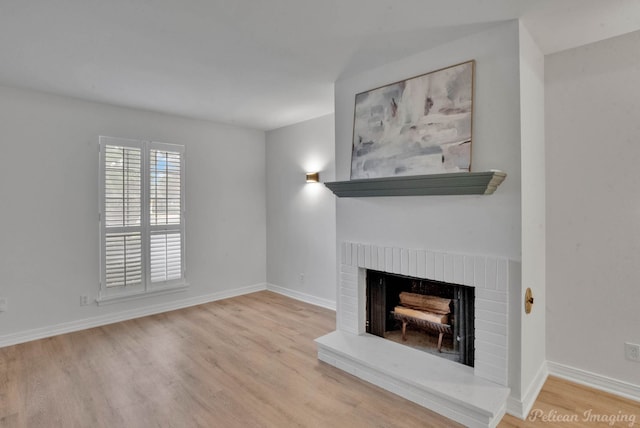 unfurnished living room with a brick fireplace and light hardwood / wood-style flooring