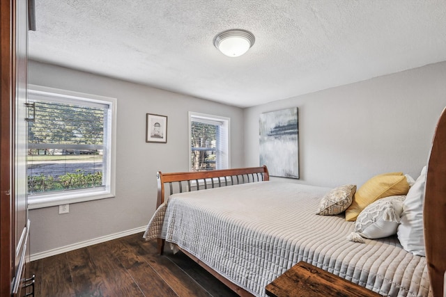 bedroom featuring multiple windows, a textured ceiling, and dark hardwood / wood-style flooring