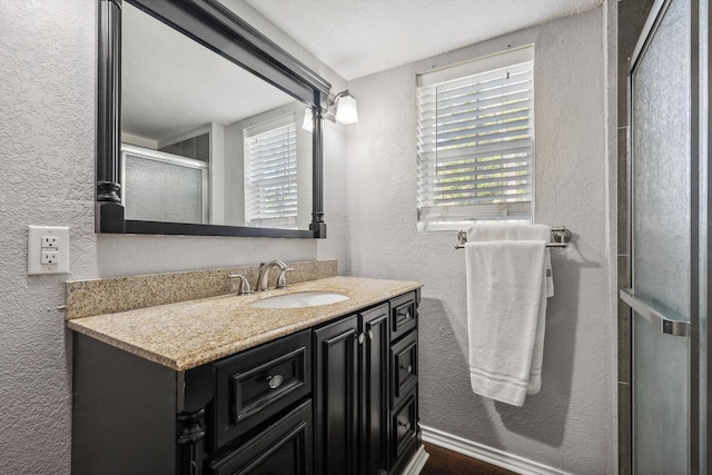 bathroom featuring walk in shower, vanity, and a textured ceiling