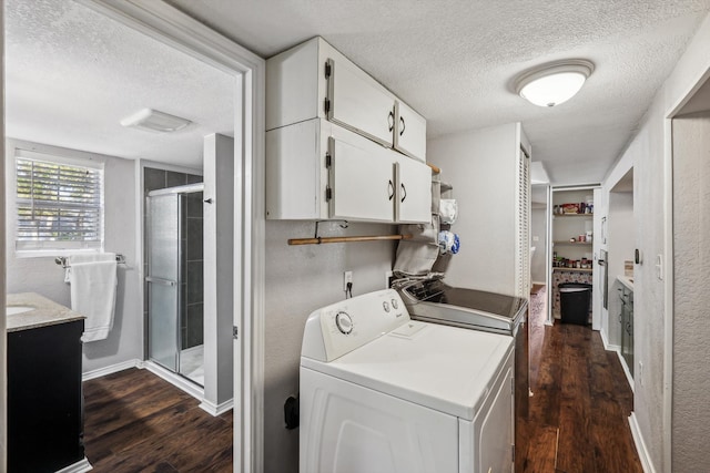 clothes washing area with dark wood-type flooring, cabinets, a textured ceiling, and independent washer and dryer