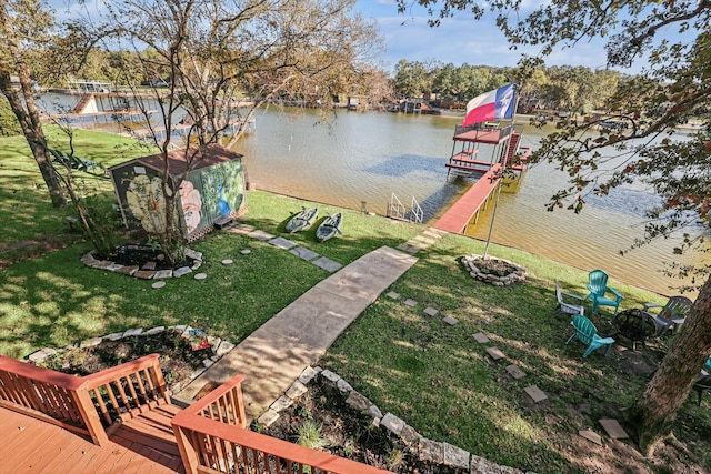 view of dock with a water view, a yard, and a fire pit