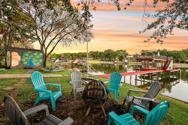 patio terrace at dusk featuring a water view and an outdoor fire pit