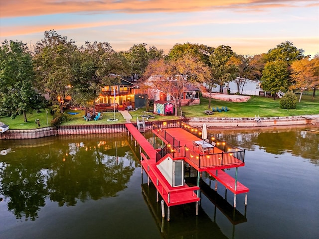 view of dock with a yard and a water view