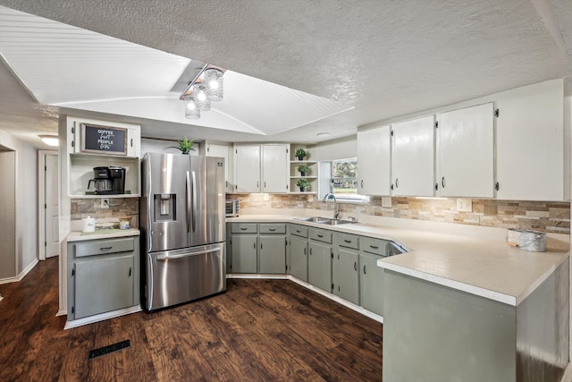 kitchen featuring sink, dark hardwood / wood-style floors, a textured ceiling, stainless steel fridge, and decorative backsplash