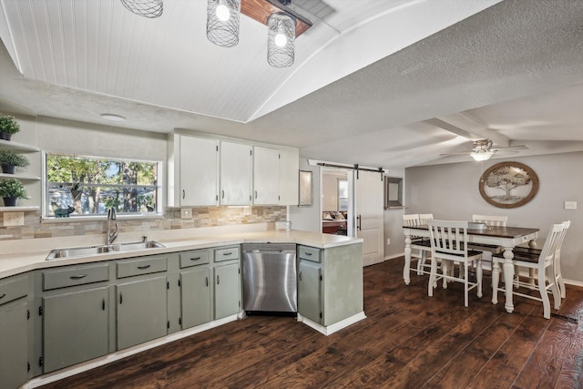 kitchen with dark wood-type flooring, a barn door, sink, stainless steel dishwasher, and lofted ceiling with beams