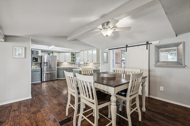 dining space with vaulted ceiling with beams, a barn door, sink, dark hardwood / wood-style floors, and ceiling fan