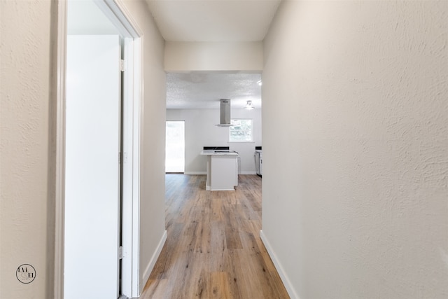 corridor with a textured ceiling and light hardwood / wood-style floors