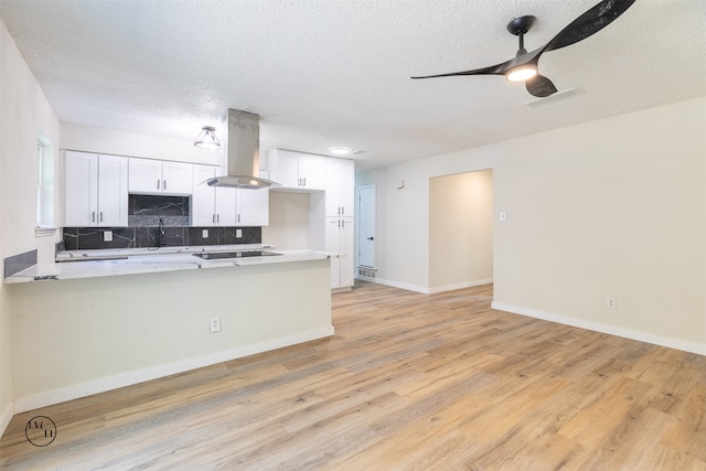 kitchen featuring white cabinetry, kitchen peninsula, tasteful backsplash, and island exhaust hood