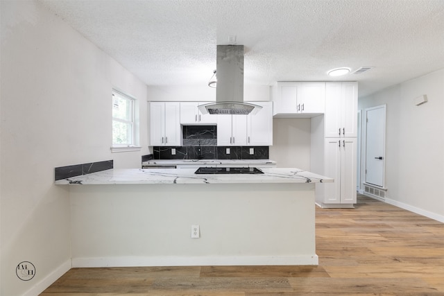 kitchen featuring island range hood, white cabinetry, and kitchen peninsula