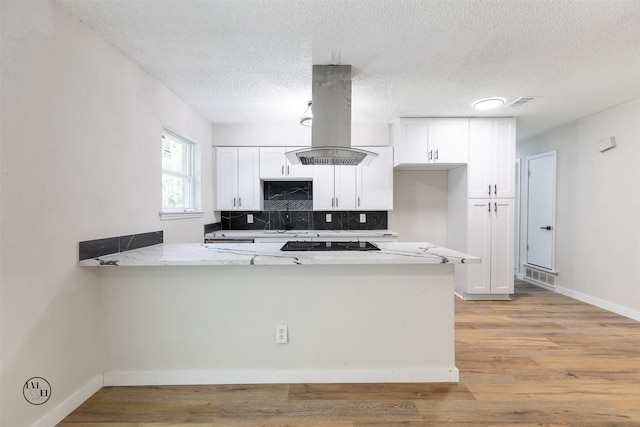 2318 May Ln, Grand Prairie, TX 75050 - kitchen featuring island exhaust hood, white cabinets, a peninsula, decorative backsplash, and light wood-style flooring