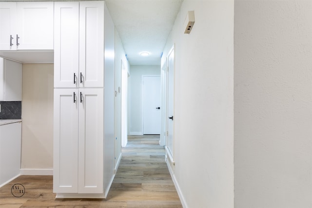 corridor featuring light hardwood / wood-style floors and a textured ceiling