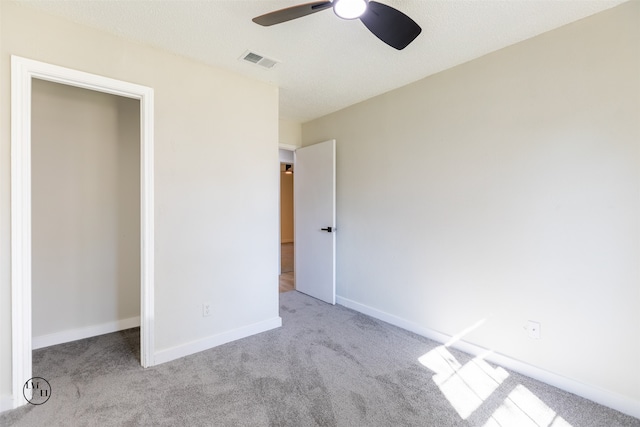 unfurnished bedroom with a textured ceiling, light carpet, and ceiling fan