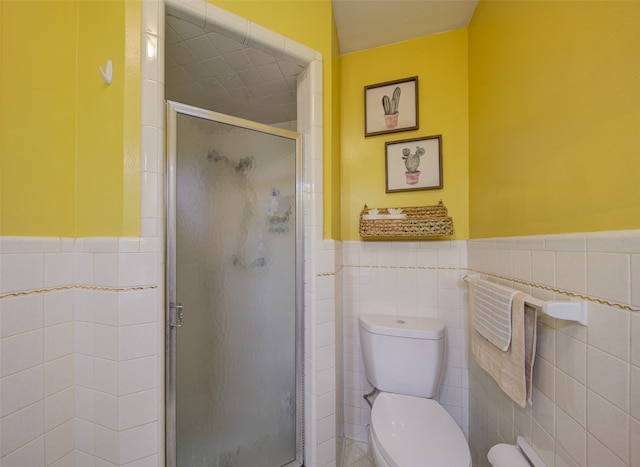 bathroom with tile walls, toilet, and a shower with door