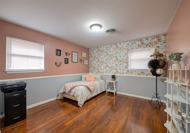 bedroom with multiple windows and dark hardwood / wood-style floors