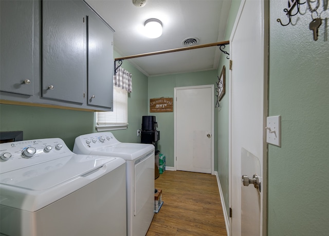 laundry room with cabinets, wood-type flooring, crown molding, and washing machine and clothes dryer