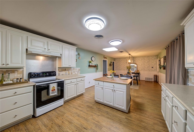 kitchen featuring a center island, white range with electric stovetop, hanging light fixtures, white cabinets, and light hardwood / wood-style flooring