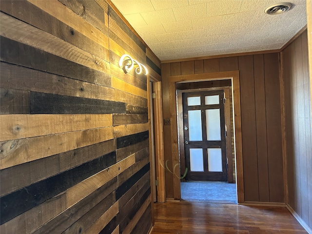 corridor featuring dark wood-type flooring and wooden walls