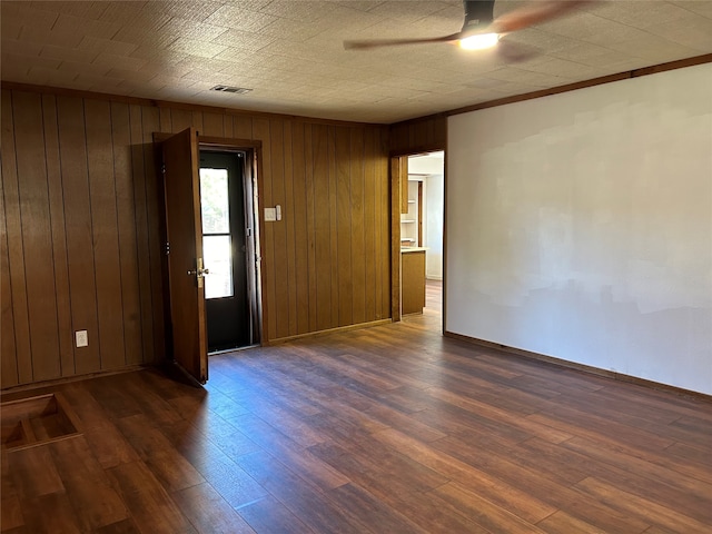 spare room with ceiling fan, wooden walls, and dark hardwood / wood-style floors