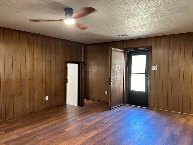 foyer featuring dark hardwood / wood-style flooring, wooden walls, and ceiling fan