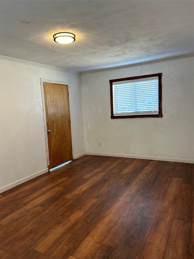 spare room with dark wood-type flooring and crown molding