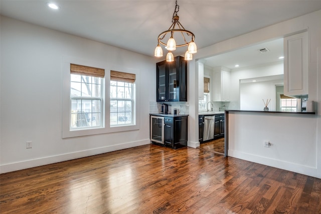 kitchen featuring beverage cooler, dishwasher, white cabinetry, an inviting chandelier, and tasteful backsplash