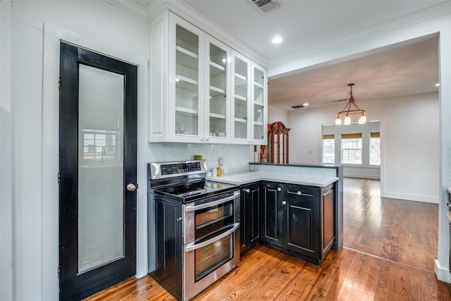 kitchen featuring tasteful backsplash, a notable chandelier, double oven range, light wood-type flooring, and white cabinets