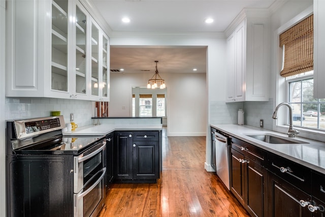 kitchen featuring stainless steel appliances, a notable chandelier, pendant lighting, white cabinets, and sink