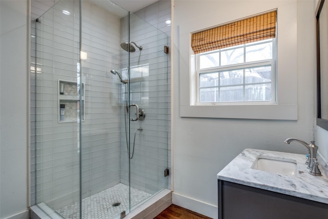 bathroom with a shower with shower door, hardwood / wood-style flooring, and vanity