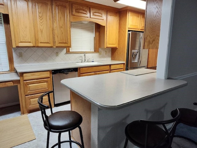 kitchen featuring stainless steel appliances, a kitchen breakfast bar, sink, and tasteful backsplash