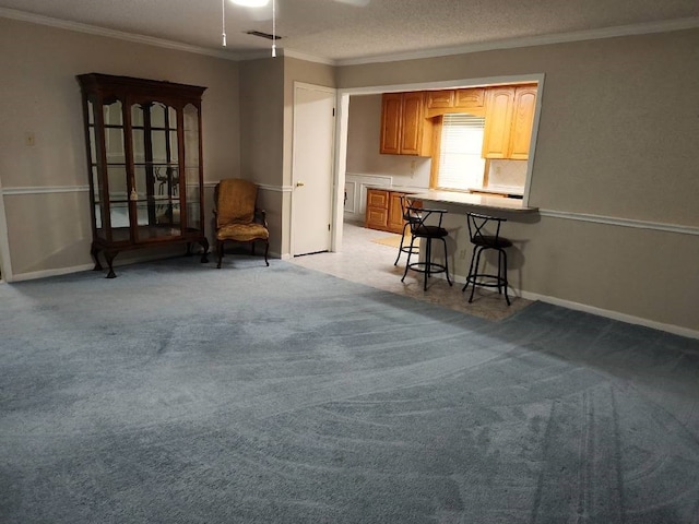 interior space featuring light colored carpet, a textured ceiling, ceiling fan, crown molding, and a breakfast bar