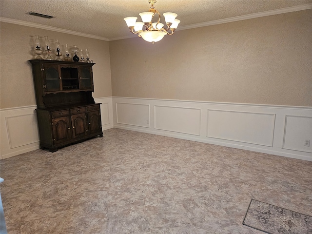 empty room featuring ornamental molding, a textured ceiling, and an inviting chandelier