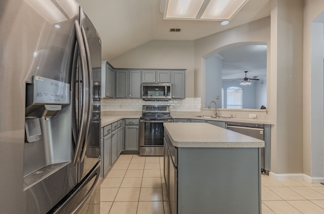 kitchen with a kitchen island, appliances with stainless steel finishes, light tile patterned floors, sink, and lofted ceiling