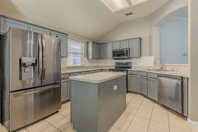 kitchen with light tile patterned flooring, sink, a kitchen island, and appliances with stainless steel finishes