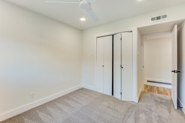 unfurnished bedroom with a closet, light colored carpet, and ceiling fan