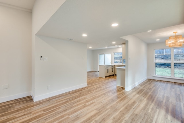 unfurnished living room featuring a notable chandelier and light hardwood / wood-style floors