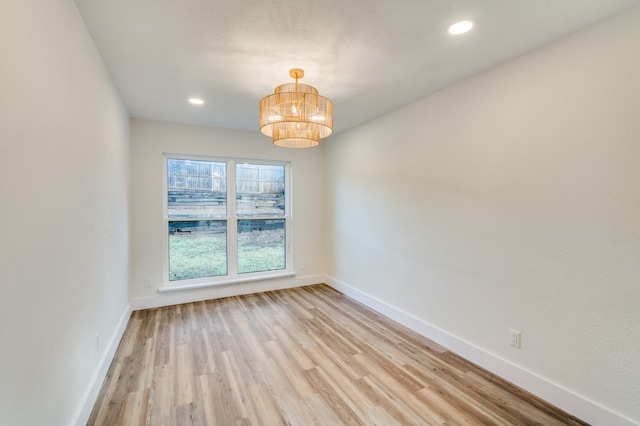 empty room featuring light wood-type flooring and a notable chandelier