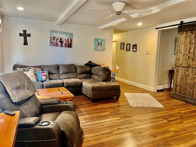 living room featuring a barn door, ceiling fan, wood walls, and hardwood / wood-style floors