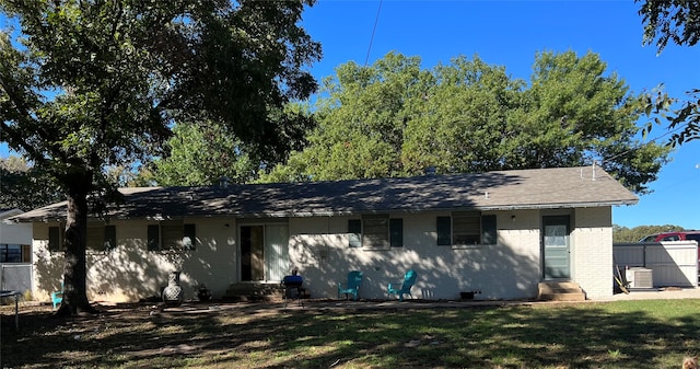 rear view of property featuring cooling unit and a lawn